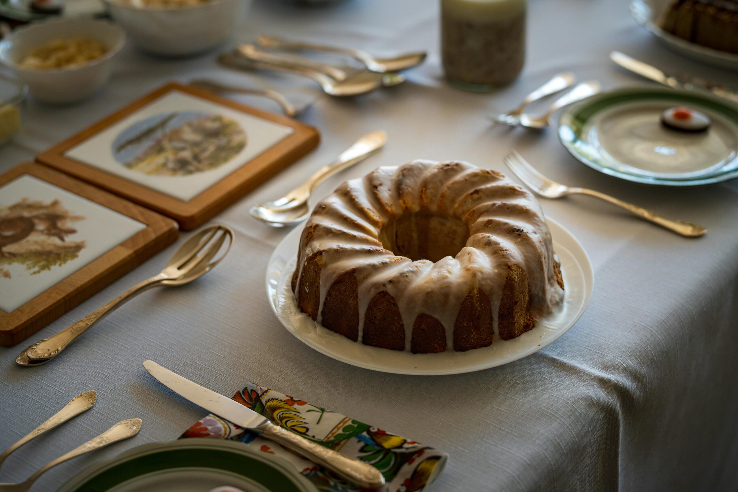 A beautifully iced Bundt cake on a dinner table set elegantly for guests in Kraków.