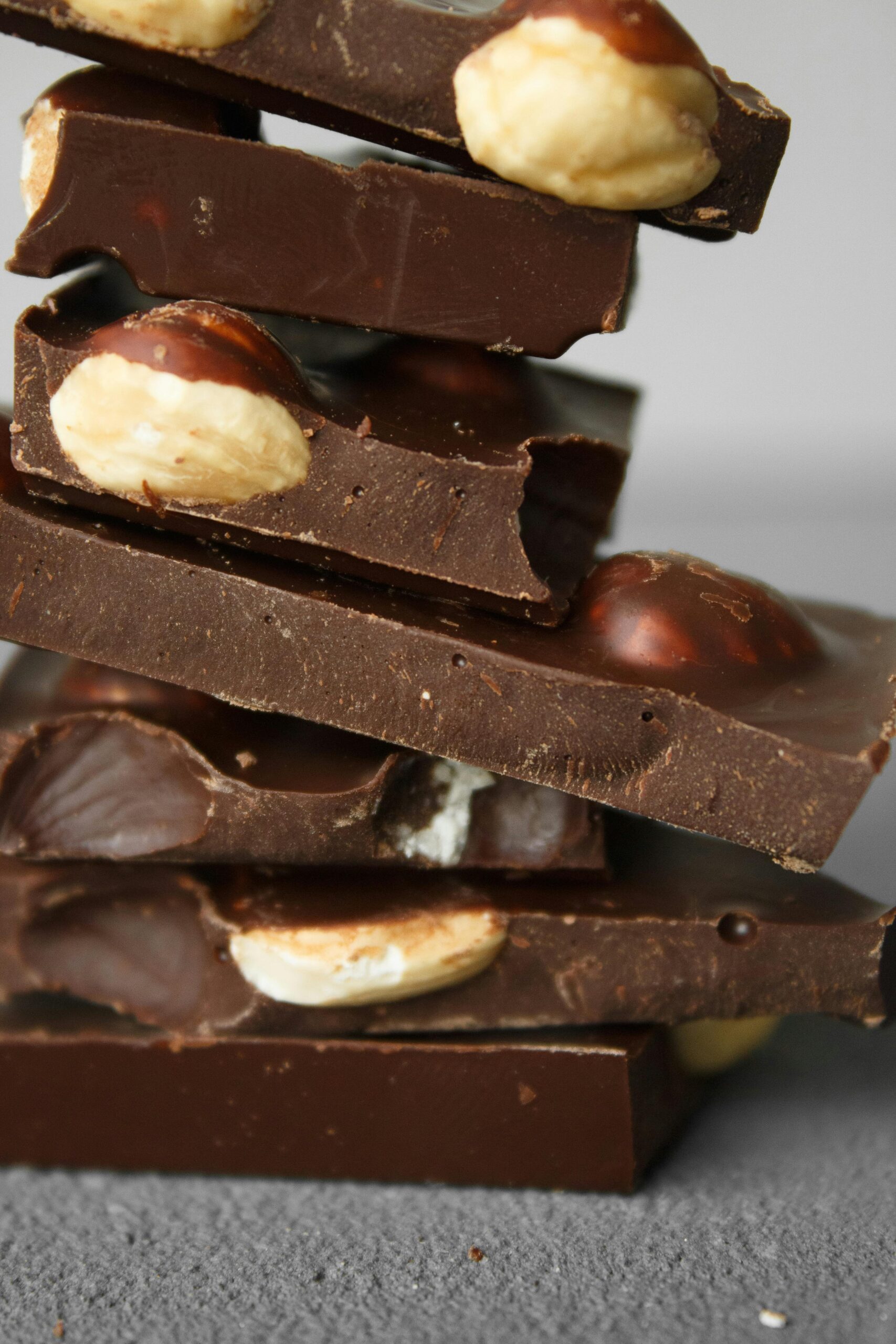 Close-up of stacked chocolate bars with whole nuts in a vertical composition.