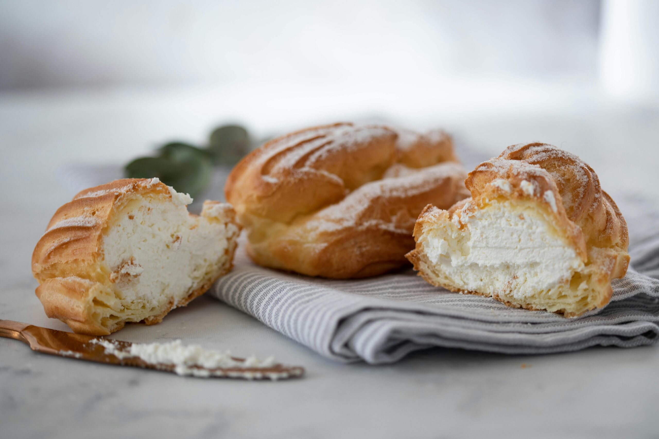 Enticing cream puffs filled with rich cream, dusted with sugar, on a napkin.